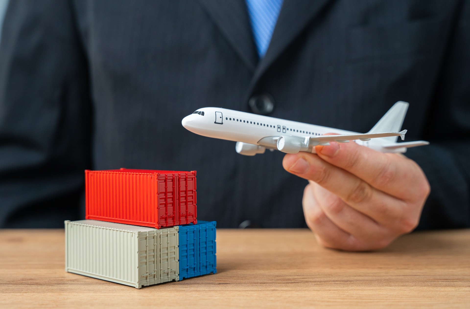 Un homme d’affaires tient un avion-cargo alors qu’il décolle au-dessus d’une pile de conteneurs maritimes. Concept de transport aérien de fret et de marchandises. Colis, commandes en ligne depuis des places de marché étrangères. Poste aérienne.