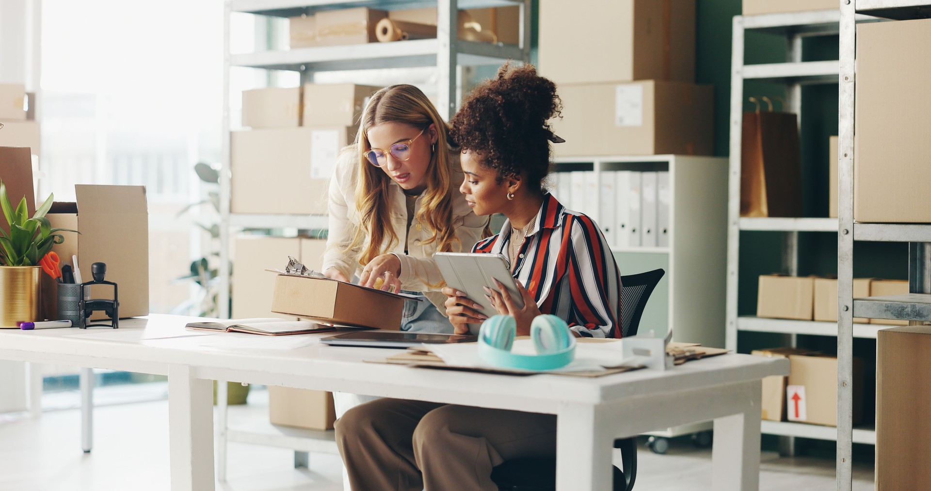 Femmes, tablette et travail d’équipe pour la logistique de bureau, colis et liste de contrôle du commerce électronique avec stock de la boutique en ligne. Petites entreprises ou vendeurs avec technologie numérique, boîte et presse-papiers pour la co